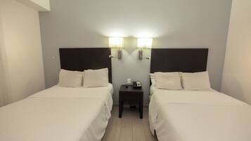 A hotel room with two single beds, a small bedside table with a phone, and wall-mounted lights.