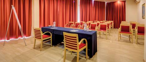 A conference room with a long table, chairs, and red curtains.