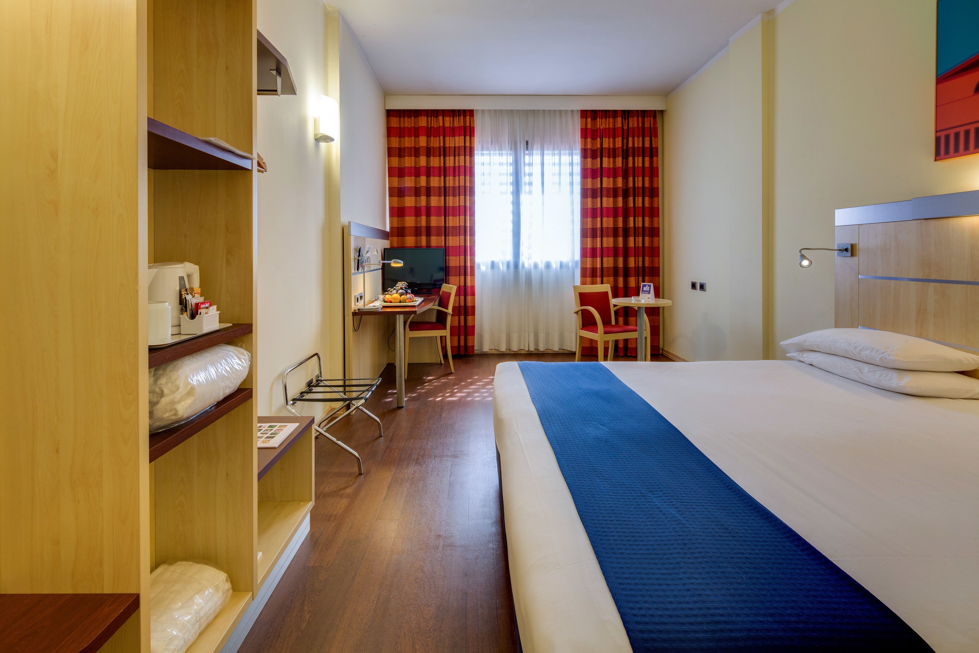 Una habitación de hotel con cama, escritorio, silla y armario.