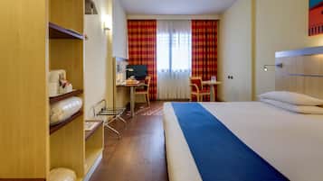 Una habitación de hotel con cama, escritorio, silla y armario.