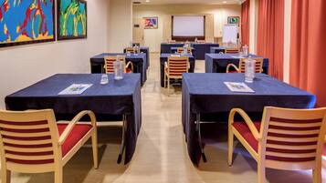 A conference room with tables, chairs, and a projector screen.