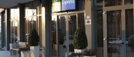 Un bâtiment de l’hôtel Holiday Inn Express doté d’une façade en verre, de grandes fenêtres et d’une enseigne au-dessus de l’entrée.