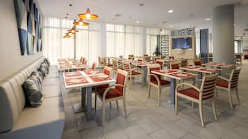 A spacious restaurant with multiple dining tables and chairs, a long bench seating area, and a large flat-screen TV mounted on the wall.