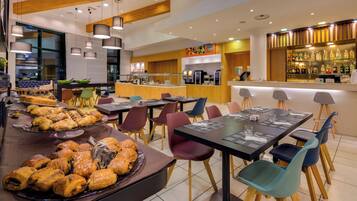 A modern cafe with a variety of pastries and sandwiches, a bar area, and a seating arrangement for guests.