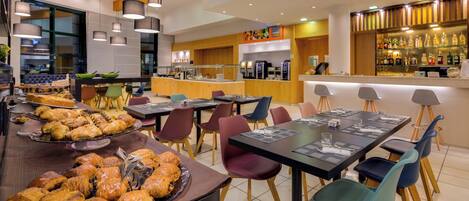 Un café moderno con una variedad de pasteles y sándwiches, una zona de bar y un espacio de esparcimiento para los clientes.