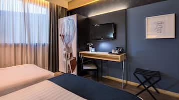 Une chambre d’hôtel avec deux lits, un bureau, une chaise, une télévision et une citation encadrée au mur.