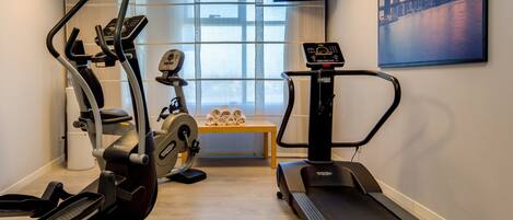 Un gimnasio con equipo de cardio, cinta de correr y máquina de remo.