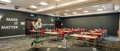 A conference room with tables, chairs, and a motivational quote on the wall.