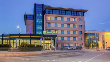 Un hôtel à plusieurs étages avec une façade en verre, une enseigne Holiday Inn et un espace de stationnement.