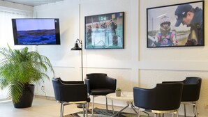 Un interior moderno con un televisor de pantalla plana grande, una planta en maceta y sillas negras alrededor de una mesa pequeña.