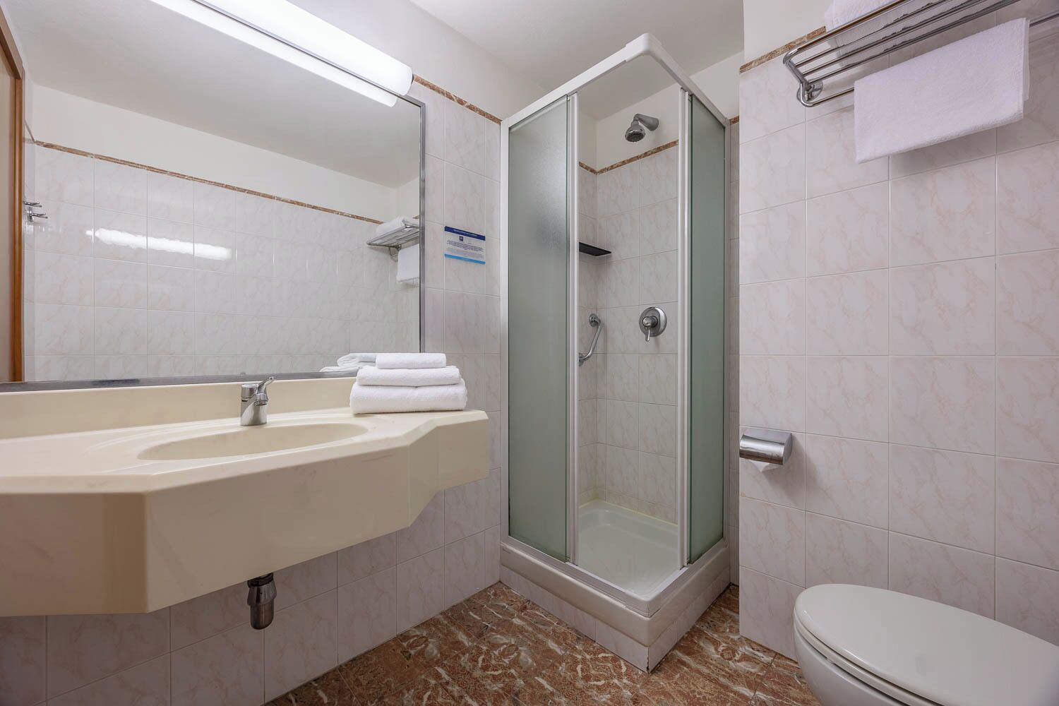 A bathroom with a sink, mirror, shower, and toilet.