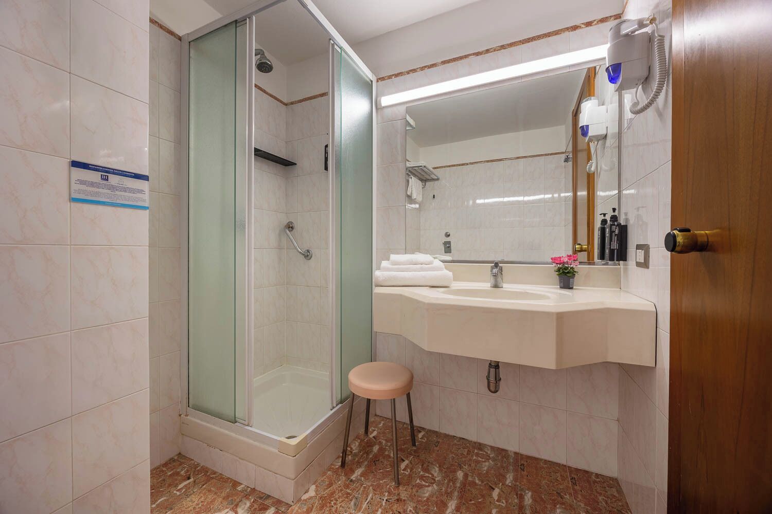 Un baño con ducha de vidrio, tocador con lavamanos y un inodoro.