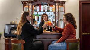 A bar area with a wooden bar counter, a coffee machine, and a liquor cabinet in the background. - IH Hotels Milano Eur Trezzano sul Naviglio (Trezzano sul Naviglio)