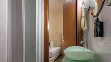 Ein modernes Badezimmer mit Duschkabine aus Glas, einem grünen Waschbecken und einer weißen Toilette.