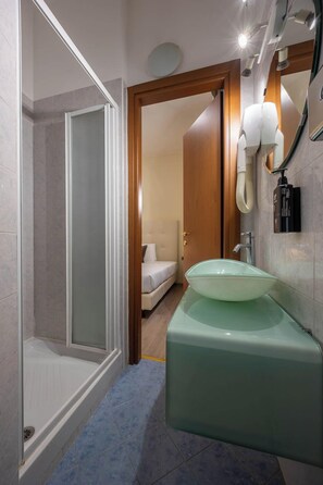 A modern bathroom with a glass shower enclosure, a green sink, and a white toilet.