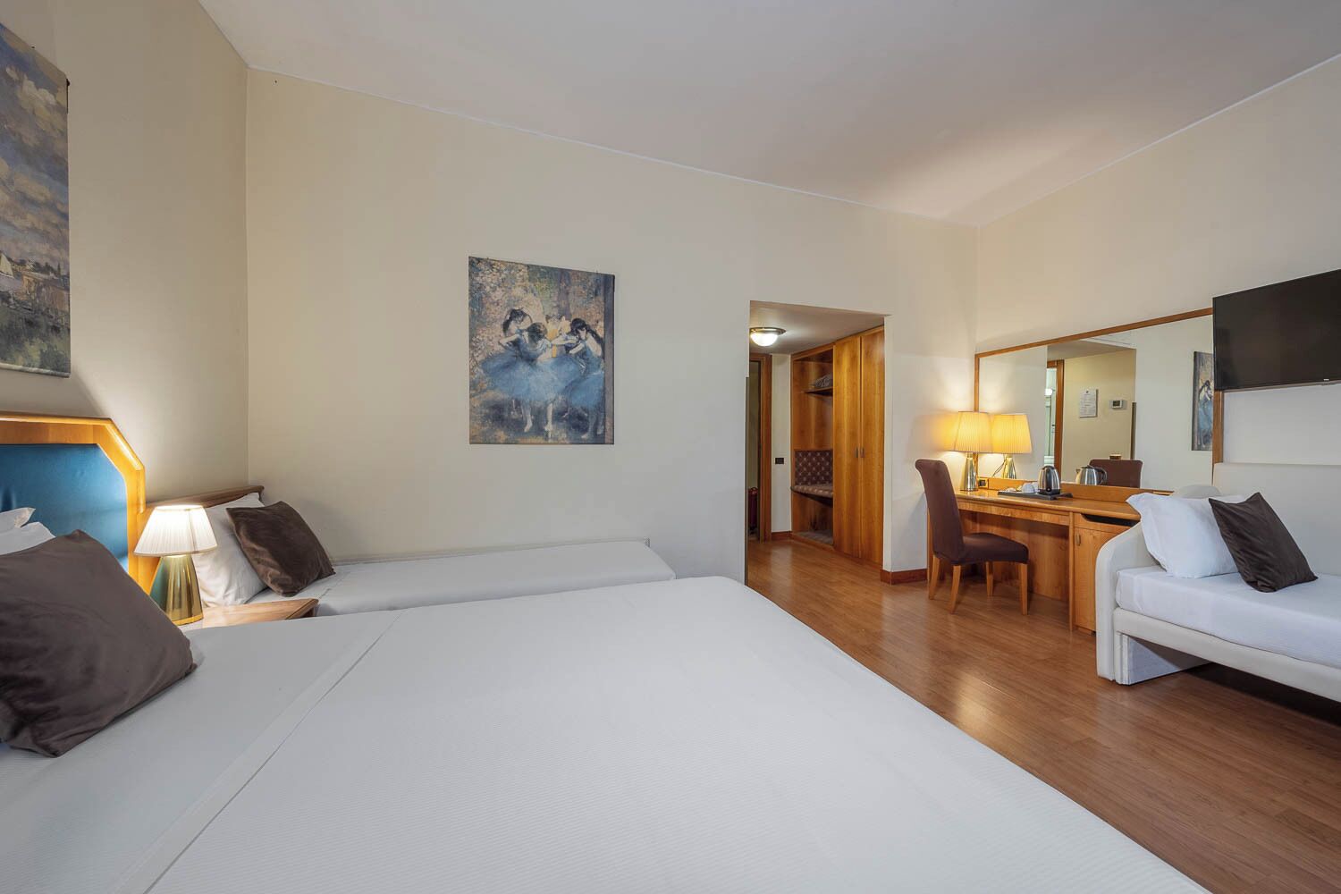 Habitación de hotel con una cama grande, un escritorio, una silla, un sofá y un cuadro en la pared.