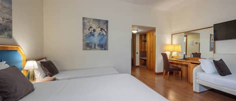Habitación de hotel con una cama grande, un escritorio, una silla, un sofá y un cuadro en la pared.