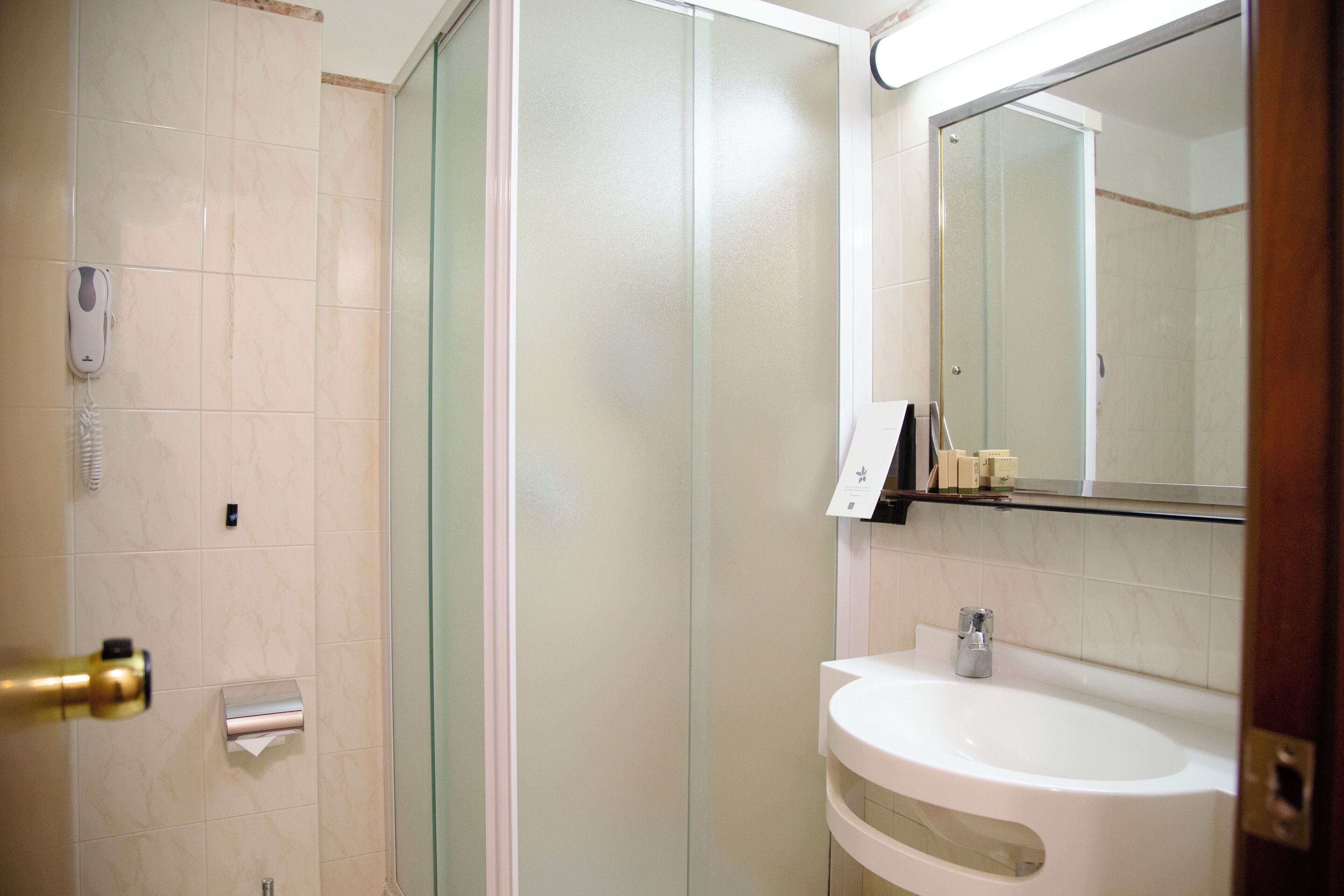 A bathroom with a glass shower enclosure, a white sink, and a mirror.