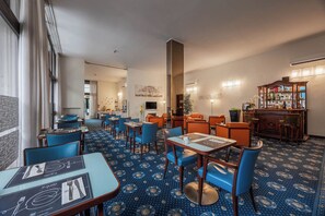 A hotel dining area with blue patterned carpet, blue chairs, and tables with menus.