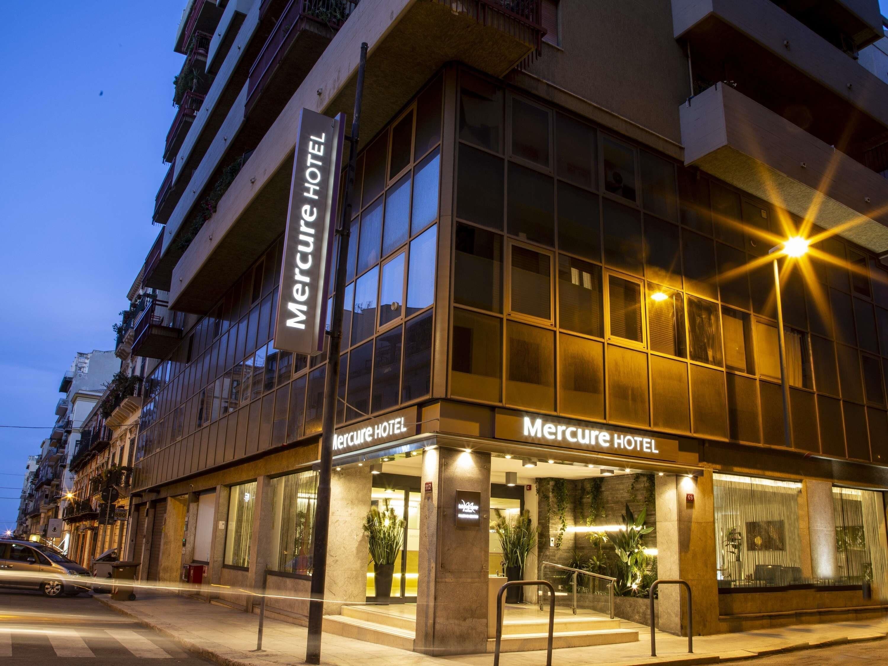 Un hôtel Mercure doté d’une façade moderne, de grandes fenêtres et d’une entrée bien éclairée.