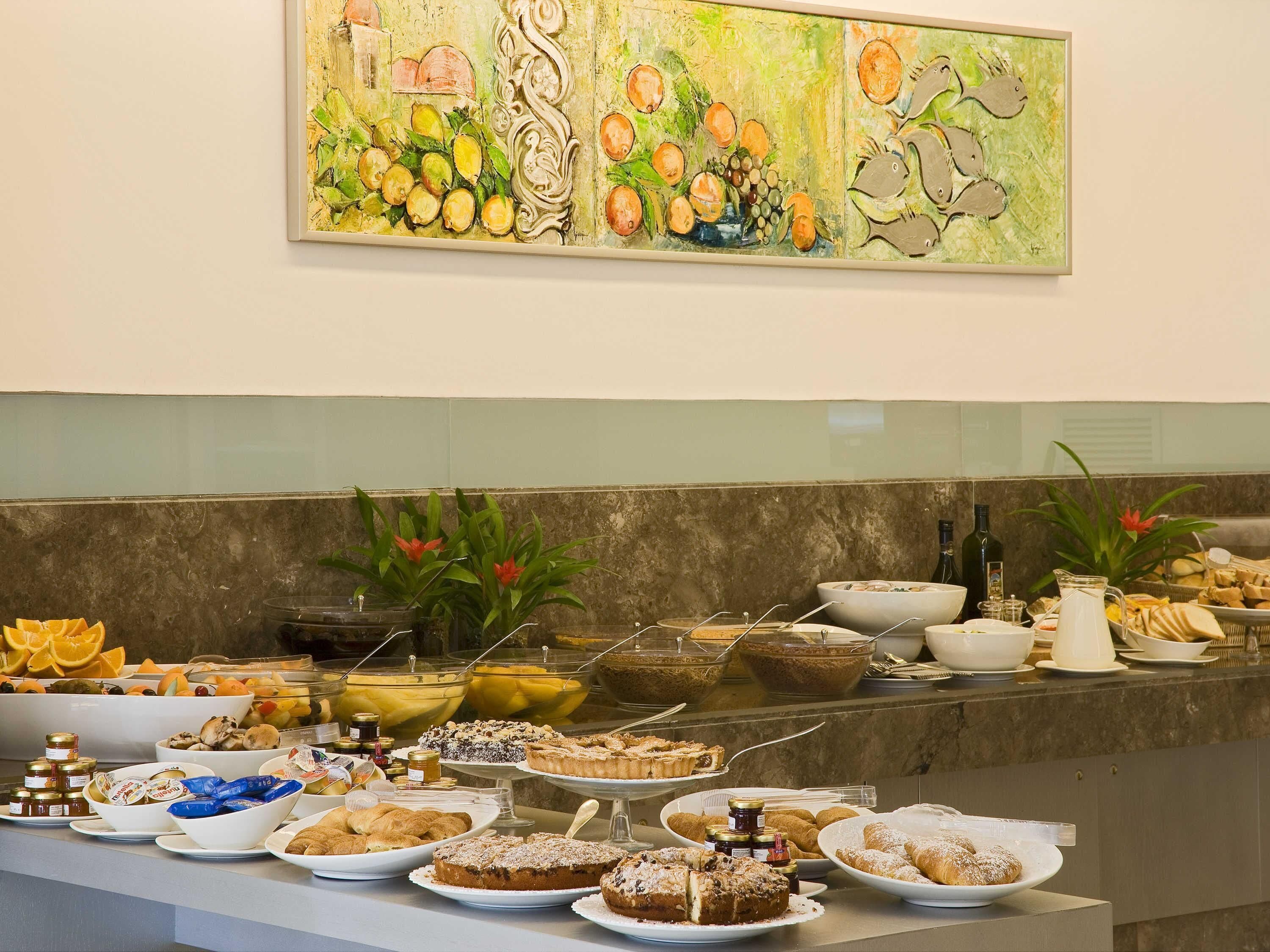 A buffet with various food items and a painting on the wall.