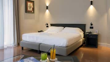 A hotel room with a large bed, bedside tables, a desk with a chair, and a window with curtains.