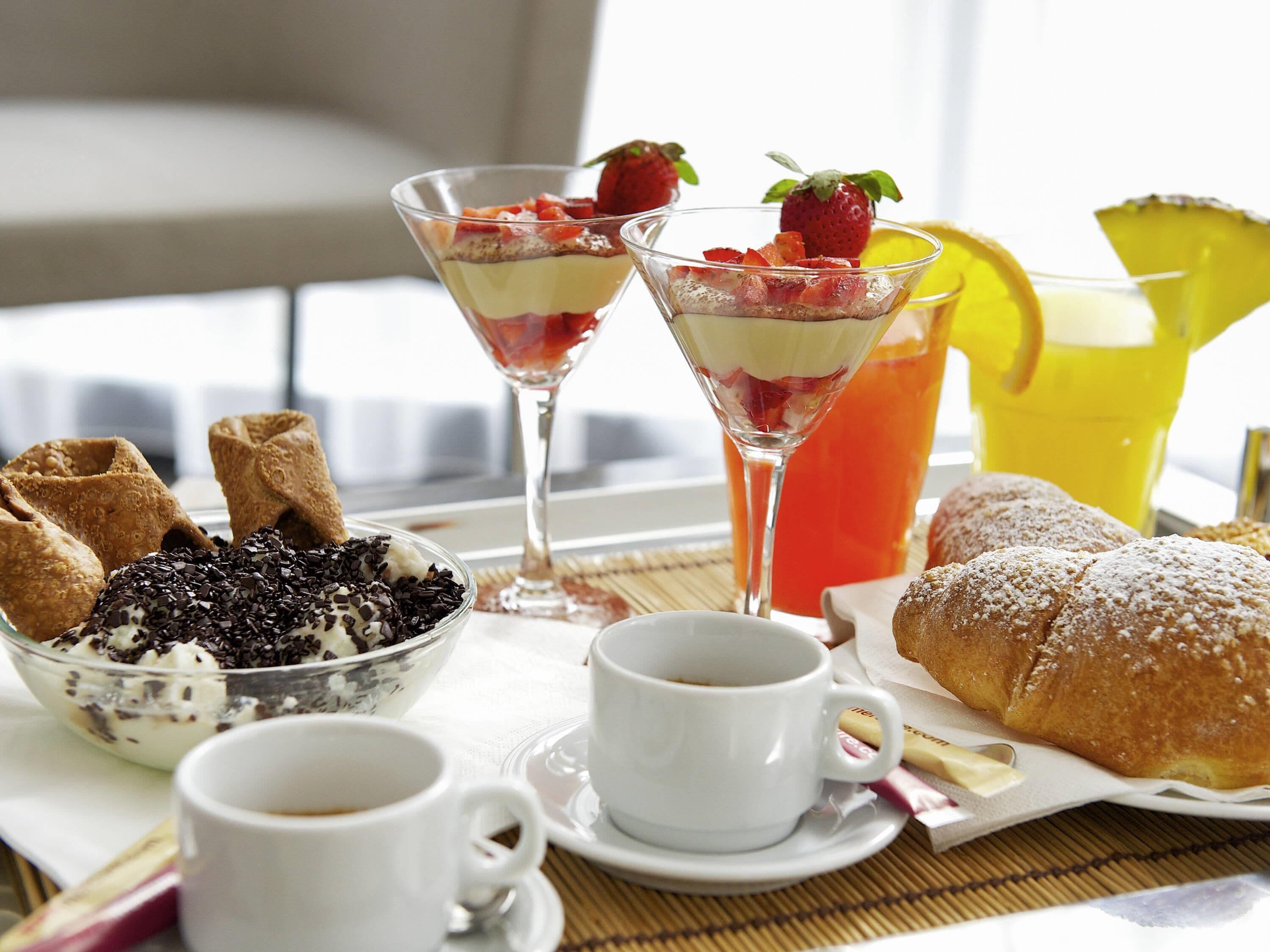 Una mesa de desayuno con postre, fruta y bebidas.