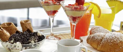 Una mesa de desayuno con postre, fruta y bebidas.