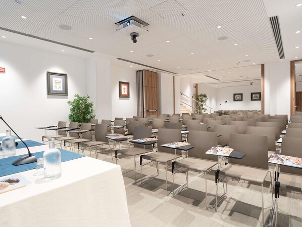 A conference room with rows of chairs, tables, a podium, and a projector. - Mercure Hotel Palermo Centro (Palermo)