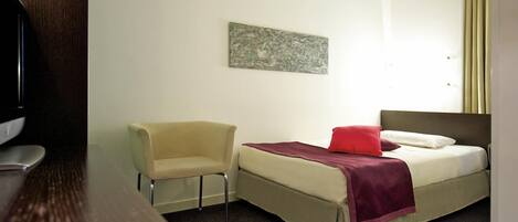 Una habitación de hotel con una cama, una silla, un televisor y un cuadro en la pared.