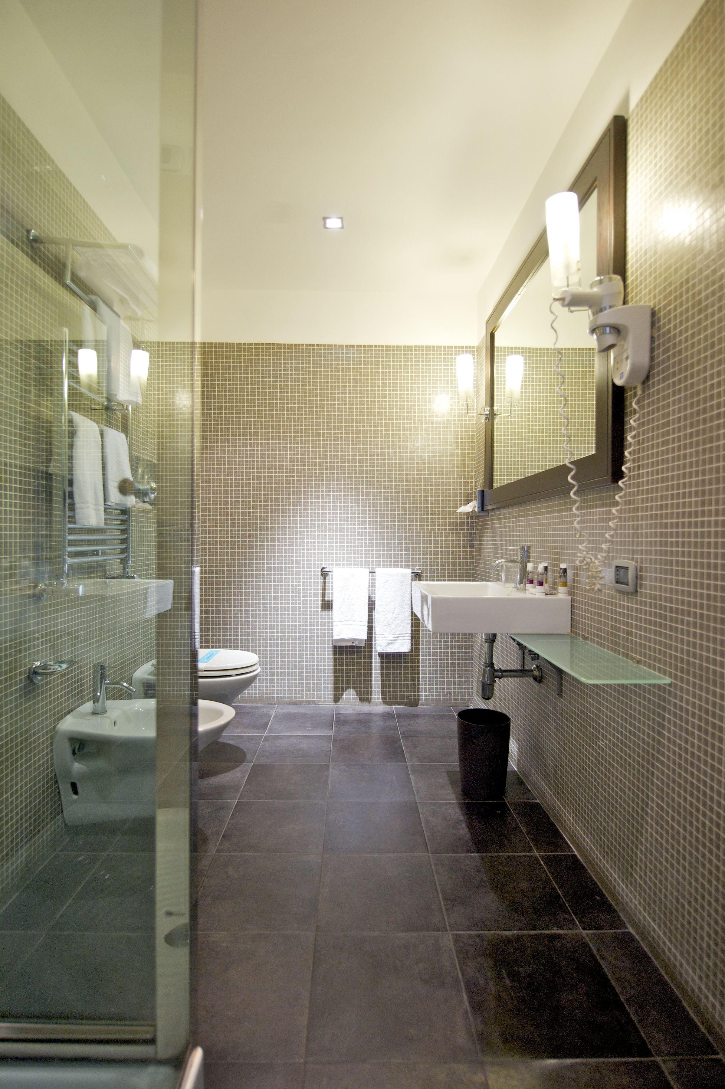 Ein modernes Badezimmer mit Duschkabine aus Glas, einem weißen Waschbecken und einer Toilette.