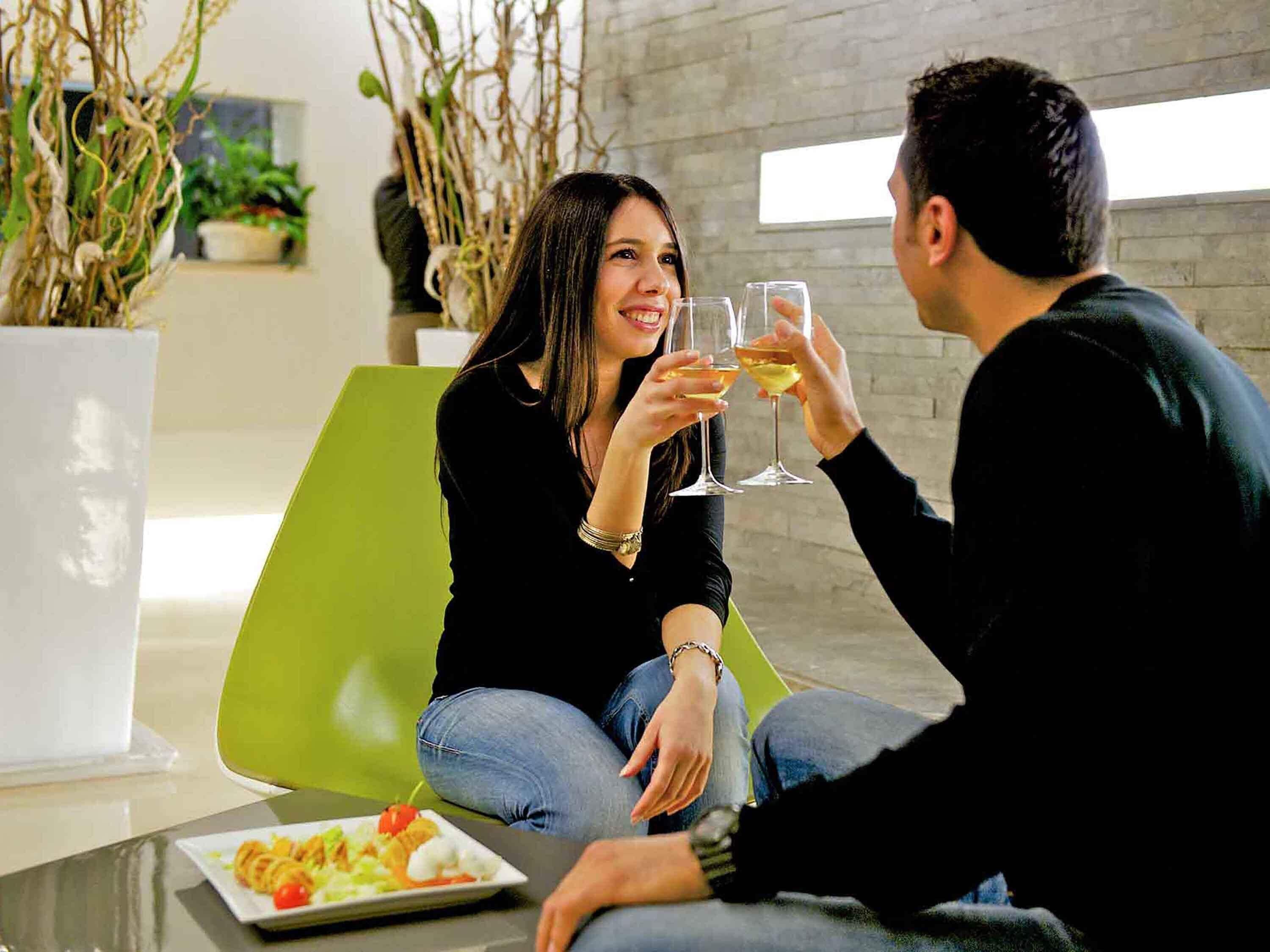 A modern interior with a green chair, a table with a plate of food, and a glass of drink.