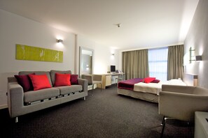 Una habitación de hotel con sofá, cama, escritorio y una silla.