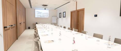 A conference room with a long table, chairs, and a projector screen.