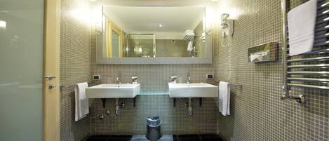 Une salle de bain moderne avec deux lavabos, un miroir et une poubelle.