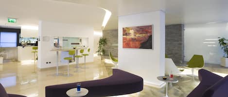 Um lobby moderno com áreas de estar, um balcão de recepção e uma grande pintura abstrata.