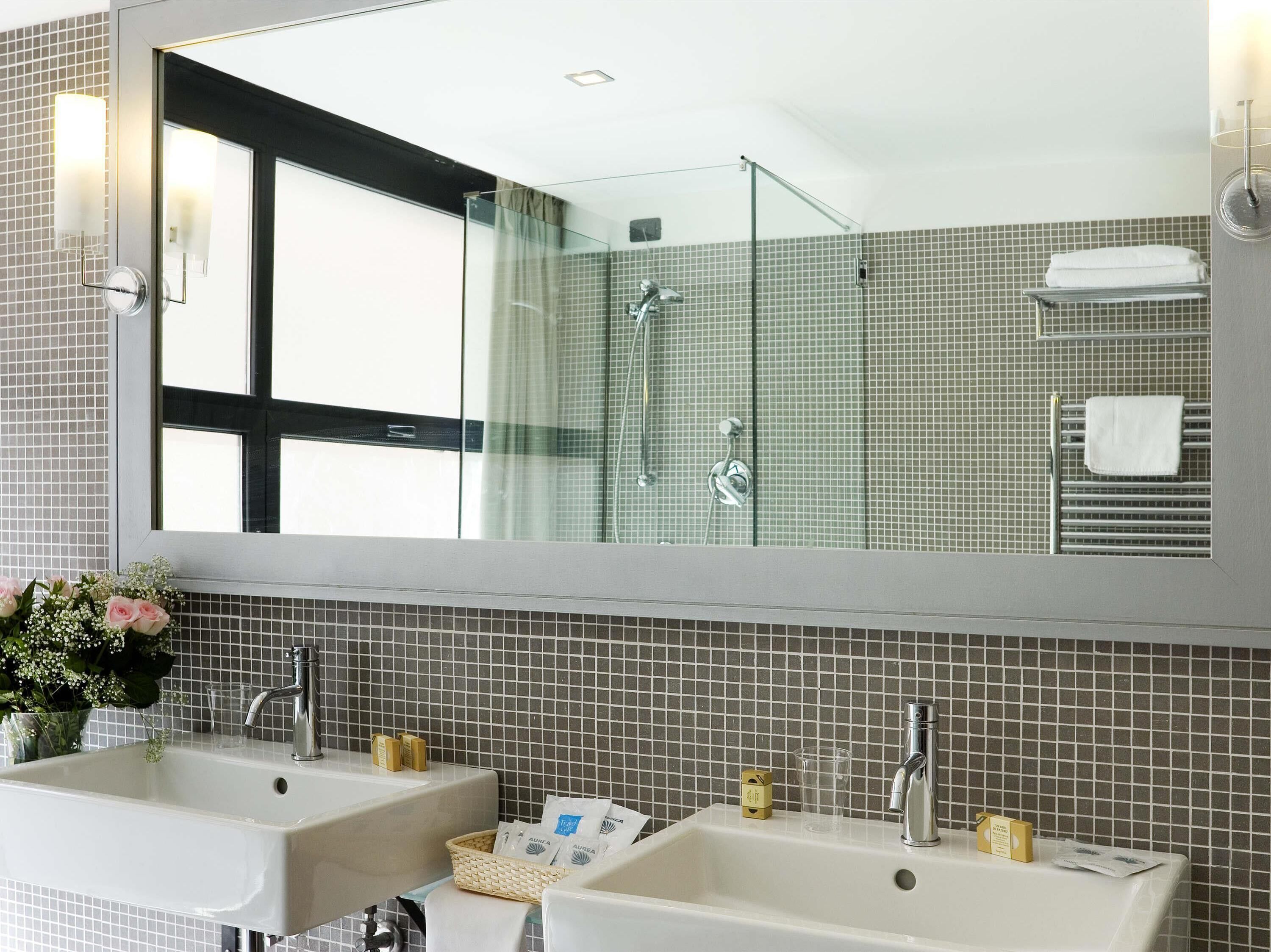 Un baño con dos lavamanos, un espejo grande y una zona de ducha.