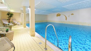 Une piscine avec un sol carrelé, des chaises longues et une fresque murale décorative.
