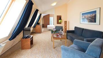 A hotel room with a bed, a desk, a sofa, a coffee table, and a large window with curtains.