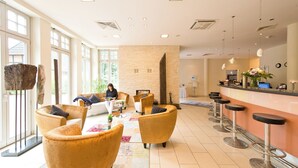 Un hall d’entrée spacieux avec un bar, des sièges confortables et une grande fenêtre laissant entrer la lumière naturelle.