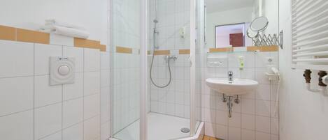 A bathroom with a glass-enclosed shower, a toilet, a sink, and a mirror.