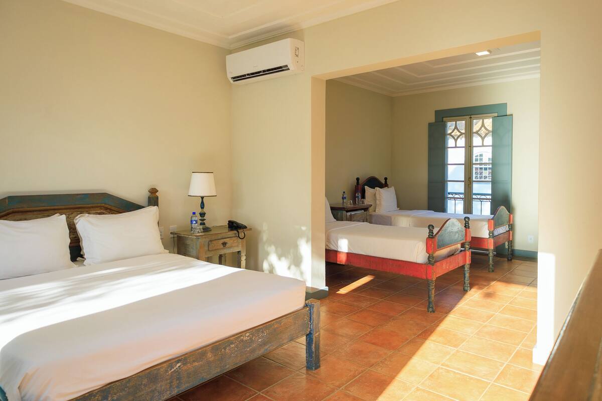 Habitación de hotel con dos camas, una mesita de noche, una lámpara y un equipo de aire acondicionado.