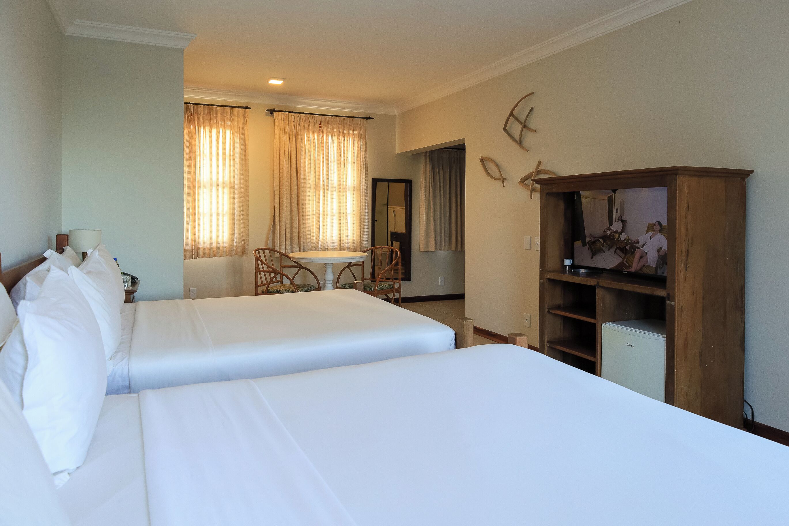 Ein Hotelzimmer mit zwei Betten, einem kleinen Tisch, einem Stuhl, einem Fernseher und einem Kleiderschrank.