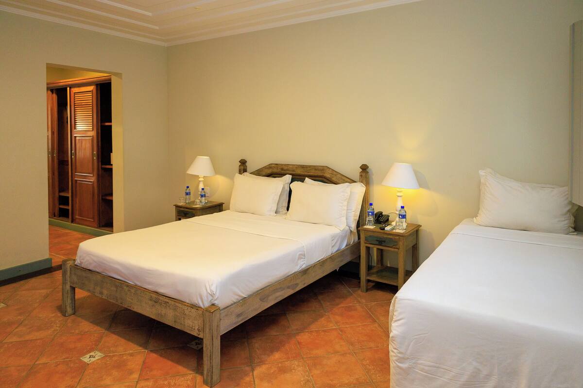 Una habitación de hotel con una cama de madera, dos mesitas de noche y una puerta que da a un armario.