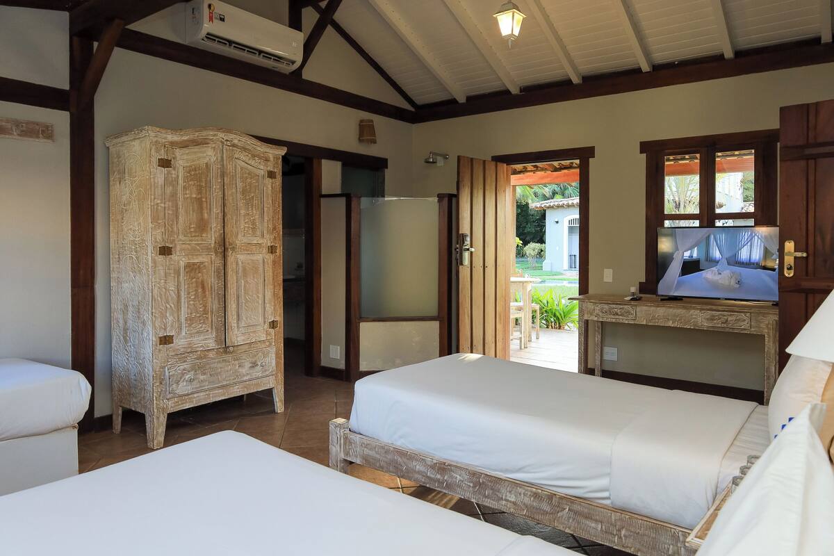 Una habitación con dos camas, un armario, un televisor y una puerta que da a un espacio al aire libre.