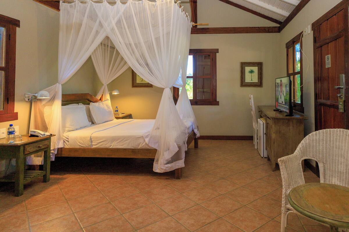Una habitación con cama, mesita de noche, una silla y televisor.