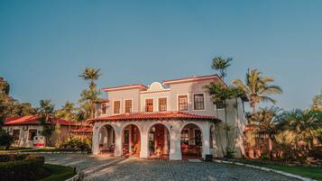 A two-story building with a red-tiled roof, multiple arches, and a cobblestone driveway.