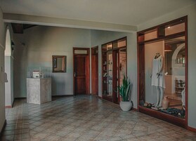 Un pasillo espacioso con suelo de baldosas, un maniquí vestido de blanco y una planta en maceta.