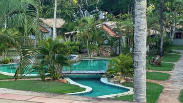 Un área de piscina con diseño curvo, rodeada de palmeras y un camino de piedra.