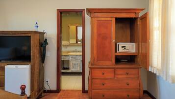 Una habitación con un armario de madera, un refrigerador pequeño y un televisor.